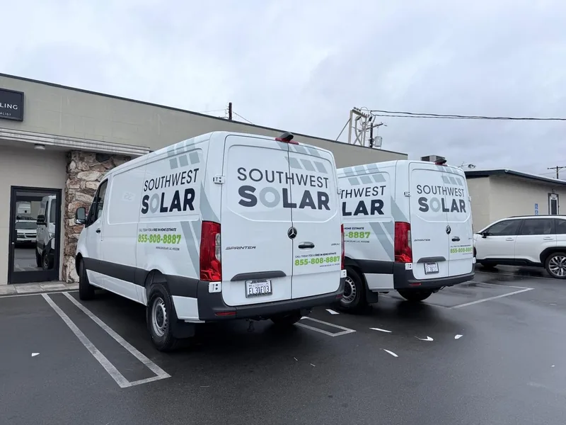 Two white Southwest Solar work vans with matching branded vehicle graphics