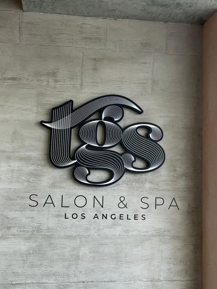 Dimensional TGS Salon and Spa logo mounted on a textured interior wall